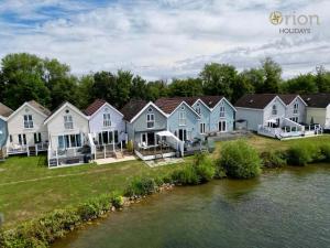 a row of houses next to a river at Spring Lake 19, The Lake House in South Cerney