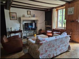 a living room with a couch and a tv at Maison de campagne rustique et confortable in Mazières-en-Gâtine