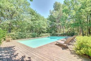 een zwembad op een houten terras met twee stoelen bij La maison Calavoun in Maubec