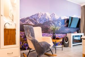 a room with a chair and a mountain mural at Apartamenty Enklawa pod Giewontem by Apart Concept Podhale in Kościelisko