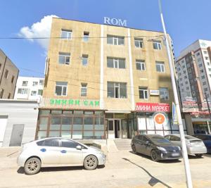 two cars parked in a parking lot in front of a building at Rom Etuga guesthouse in Ulaanbaatar