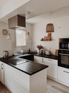 a kitchen with white cabinets and a black counter top at Le gîte de Marceau in Labergement-lès-Auxonne
