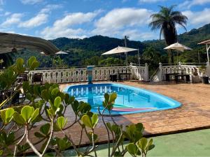 a swimming pool with a fence and a palm tree at Pousada Encantos da Serra Macacos in Macacos