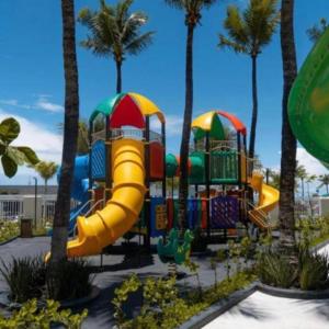 un parco giochi con scivolo in un parco con palme di Salinas Premium Resort - TWF a Salinópolis