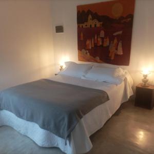 Un dormitorio con una cama blanca con dos lámparas. en La casita anaranjá, en Villa Allende