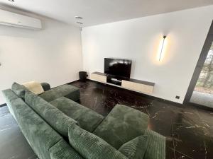 a living room with a couch and a flat screen tv at Serenity Lodge Durbuy - Sauna & Jacuzzi in Durbuy