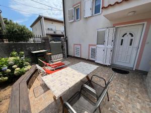 un patio avec une table et des chaises devant une maison dans l'établissement Apartmani Rosa, à Jadranovo