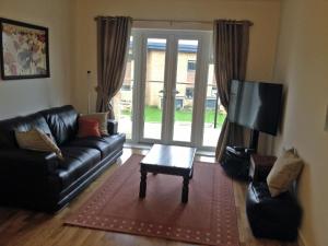 a living room with a couch and a tv and a table at Stockley Apartments in West Drayton