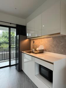 eine Küche mit weißen Schränken und einer Theke mit Kühlschrank in der Unterkunft P One Apartments in Chalong 