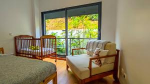 Un dormitorio con una cama y una silla y una ventana. en AL Vista Alegre, en Horta