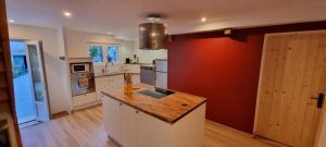 a kitchen with white cabinets and a red wall at Le Petit Pennerest in Noyal-Pontivy