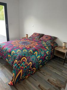 un lit avec une couette colorée dans une chambre dans l'établissement Villa Détente, à Hourtin