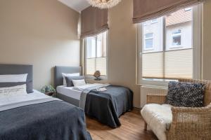 a bedroom with two beds and a chair and a window at Rodehuus Wohnung 1 in Borkum