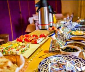 un lungo tavolo con piatti di cibo sopra di Erg Elysia Camp a Merzouga