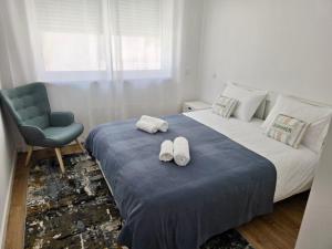 1 dormitorio con 1 cama con silla y 2 toallas en Alojamento Xaandar Beach Spot, en Nazaré