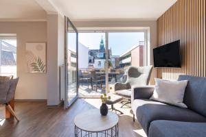a living room with a couch and chairs and a tv at Wittehuus Wohnung 3 in Borkum