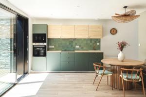 a kitchen with green cabinets and a wooden table at Cosy home quartier gare lafayette avec spa et sauna privatif in Angers