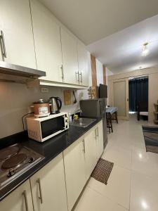 a kitchen with a microwave and a sink at Sea Residences MOA Pasay City - Rose Staycation in Manila