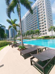 a pool with picnic tables and a large building at Sea Residences MOA Pasay City - Rose Staycation in Manila