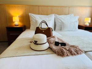 een hotelkamer met een hoed en een zonnebril op een bed bij Plaza Hotel Gyula in Gyula