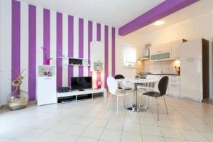 eine Küche mit lila und weißen Wänden sowie einem Tisch und Stühlen in der Unterkunft Apartments Nenich Aves in Žman