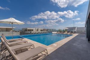 a swimming pool with lounge chairs and an umbrella at Always Playa at IPANA in Playa del Carmen