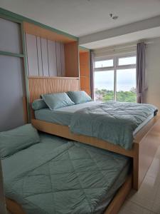 a bedroom with two beds and a window at PENTAPOLIS WONGKITO APARTMENT di pusat kota Balikpapan in Stalkudo