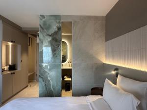 1 dormitorio con cama blanca y pared de mármol en James Vignoble Hôtel, Eguisheim, en Eguisheim