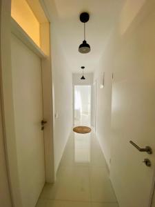 a hallway with white walls and a door with a stool at Apartmani PERLA 55 in Poreč +47 photos