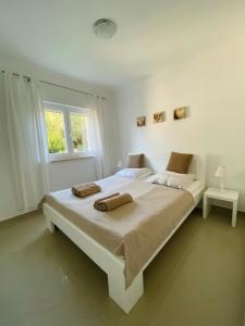 a white bedroom with a large bed with two towels on it at Apartmani PERLA 55 in Poreč