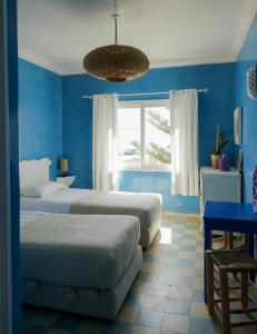 a blue bedroom with two beds and a window at Blue Kaouki Boutique Hotel in Sidi Kaouki