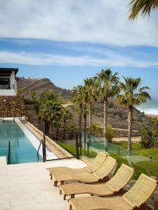 a group of chairs sitting next to a swimming pool at CocoBeach Mojácar - 3 min a pie de Playa Macenas in Mojácar