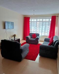 una sala de estar con 2 sofás y una alfombra roja en BlissBerry Homes, en Nairobi
