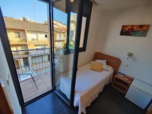 a small bedroom with a bed and a balcony at Hostal Manel in Pineda de Mar