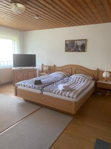 a bedroom with a wooden bed and a television at Ferienwohnungen Gebhard in Scheidegg