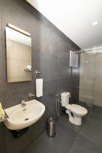 a bathroom with a sink and a toilet and a mirror at Hotel Luciya Palace in Trichūr