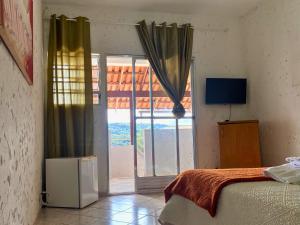 a bedroom with a bed and a sliding glass door at Pousada Encantos da Serra Macacos in Macacos
