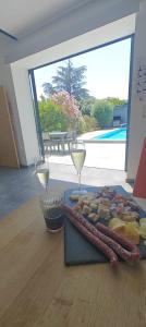 a plate of food and two wine glasses on a table at Belle Maison de vacances avec piscine. in Marquixanes
