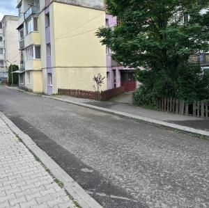 an empty street with a yellow building and trees at Gold Vibe Apartment in Topliţa