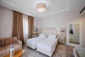 サランダにあるHotel Sejkoの白いベッドとソファが備わるホテルルームです。