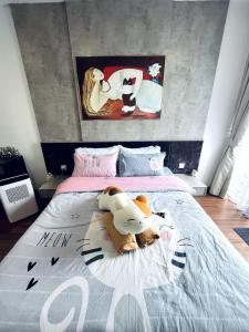 a bed with a stuffed cow laying on it at Neko Homes at i-City - WiFi TV Box 1 Carpark in Shah Alam