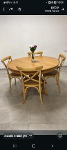 a wooden table with two chairs and a vase with flowers at הבית של רביבו in Sderot