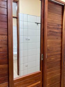 a bathroom with a wooden door and a mirror at Tai Africa Guest Rooms in Arusha