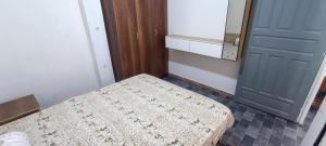 a small room with a bed and a blue door at Top F2 pied dans eau in 'Aïn Taya