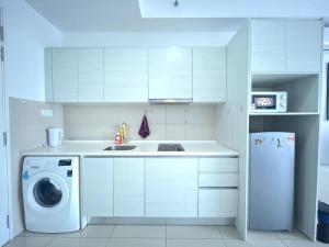 a white kitchen with a washing machine and a washer at Oasis Homes at i-City - WiFi TV Box and 1 Carpark in Shah Alam +11 photos