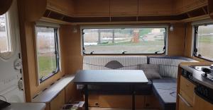 a small room with a table and two windows at Domek, caravaning nad jeziorem, Giże in Giże