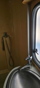 een wastafel met een kraan naast een spiegel bij Domek, caravaning nad jeziorem, Giże in Giże