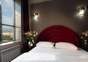 アルマトイにあるLa Talle apart hotelの窓のある部屋にある赤いヘッドボードのベッド