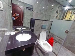 a person taking a picture of a bathroom with a toilet and sink at FLORA INN Gokarna in Gokarna