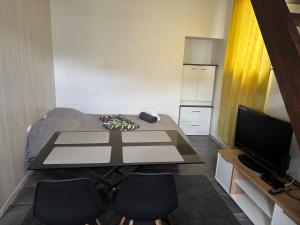 a small room with a table and a television at Pétale in Bourg-le-Roi